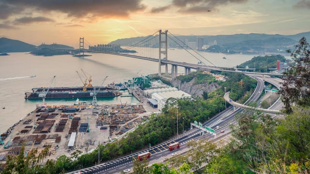 Scenic aerial view of Tsing Ma Bridge, Hong Kong with urban landscape and waterfront at sunset.