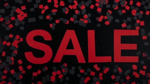 Vibrant sale banner with red text and confetti. Perfect for marketing promotions.