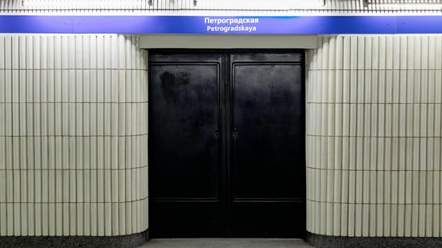Entrance to Petrogradskaya Metro Station with ribbed white walls and black doors.