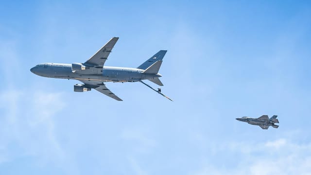 Aerial view of a KC-46 Pegasus and F-35 fighter jet flying in clear skies.