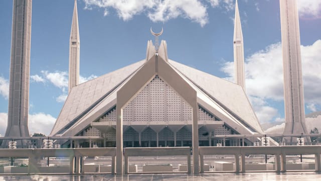 Iconic view of Faisal Mosque in Islamabad, Pakistan, under a bright blue sky with clouds.