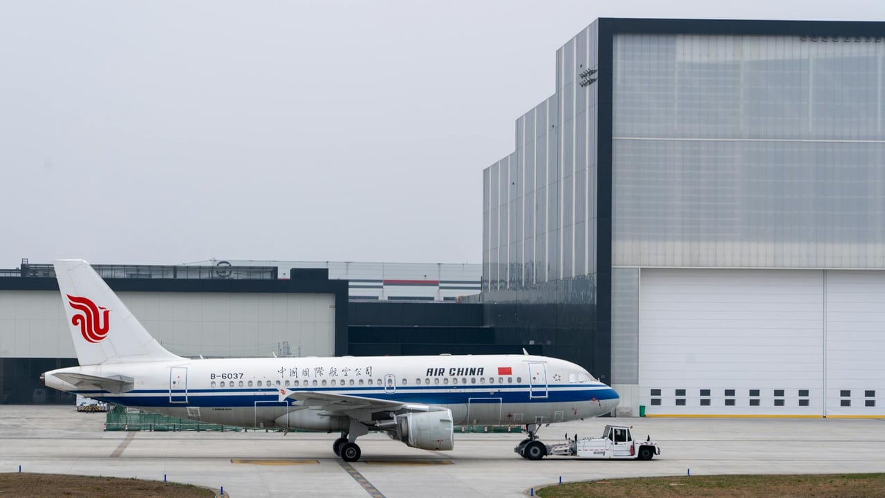Air China plane parked at an airport hangar on a cloudy day, ready for takeoff.