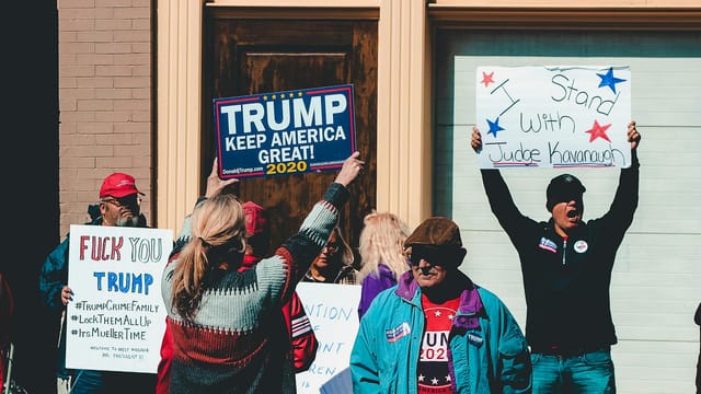 A group of people at a political rally in Wheeling, West Virginia, supporting different 2020 election campaigns.