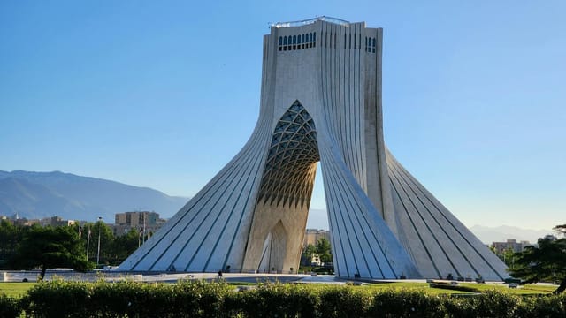 A stunning view of the Azadi Tower in Tehran, Iran, showcasing its unique architecture against a clear blue sky.