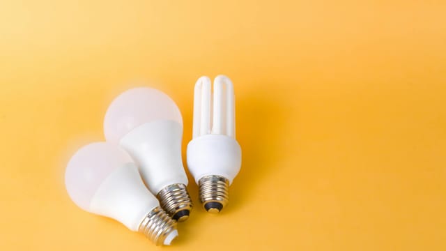 Bright and efficient LED and CFL bulbs on vibrant yellow backdrop.