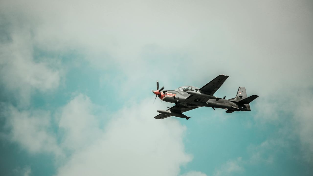 A military aircraft flying through a bright cloudy sky, showcasing aviation power.