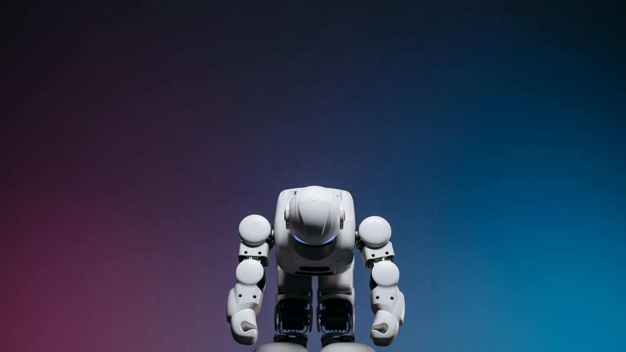 White robot in a bowing pose against a gradient studio background.