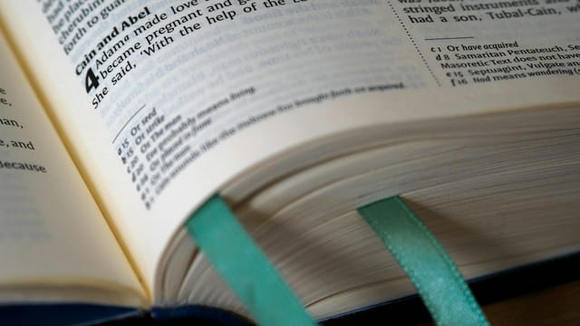 Open Bible showing Genesis, Cain and Abel story, with teal bookmarks.