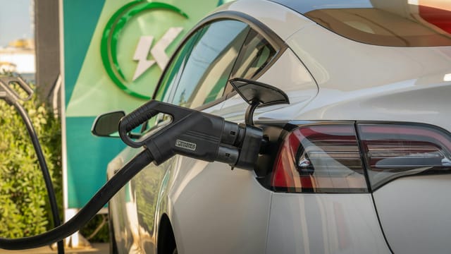 Close-up of Tesla Model 3 connected to a charging station, highlighting eco-friendly transportation.