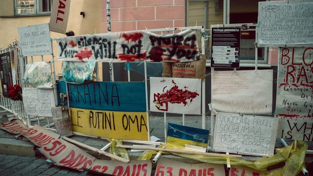 Colorful protest banners in Tallinn advocating for Ukraine and peace.
