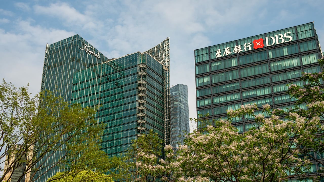 Modern skyscrapers in Shanghai's Pudong District, surrounded by spring blossoms and greenery.
