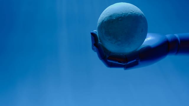 A robotic hand holds a glowing celestial sphere against a blue background, evoking a futuristic theme.
