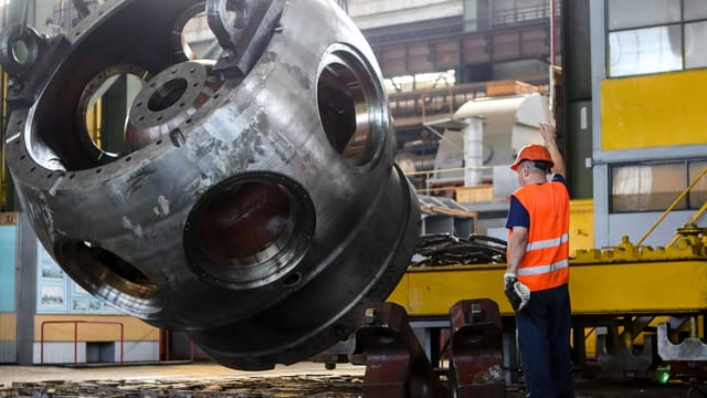 Worker in safety gear operating machinery inside an industrial plant.