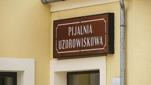 Close-up of a traditional spa sign in Krynica-Zdrój, showcasing architectural details.
