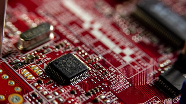 Detailed macro shot of a red circuit board, highlighting electronic components and microchips.