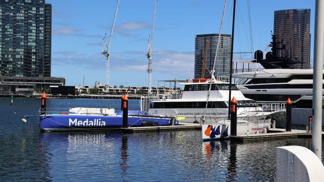 Yachts docked at a bustling urban marina under a clear blue sky, ideal for travel and leisure themes.
