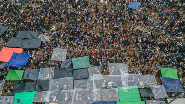 Vibrant aerial shot of a crowded outdoor market with colorful tents and people.