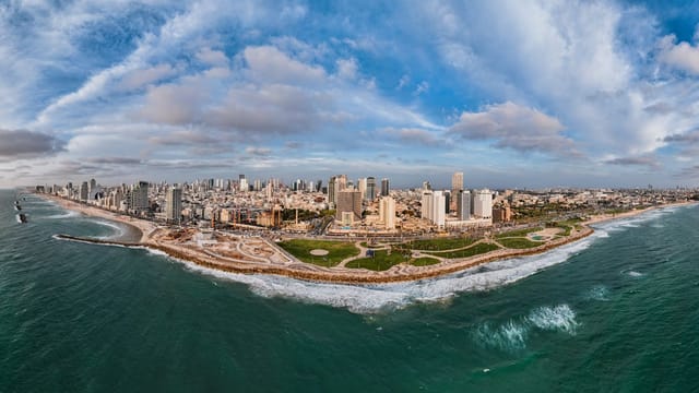 Panoramic aerial view of Tel Aviv's coastline showcasing urban skyline and Mediterranean Sea.