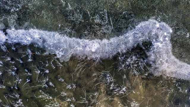 Aerial view capturing the intricate ice formations on a frozen lake during winter in Minneiska, Minnesota.