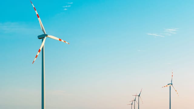 A serene image of wind turbines against a bright blue sky, symbolizing sustainable energy.
