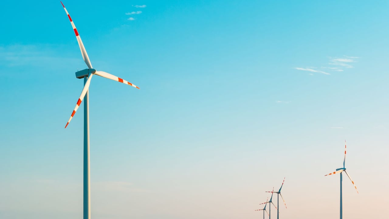 A serene image of wind turbines against a bright blue sky, symbolizing sustainable energy.