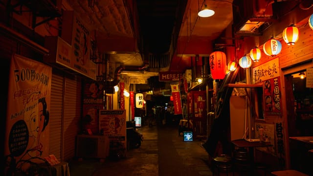 Narrow walkway between street shops with shiny lamps in Asian town at night