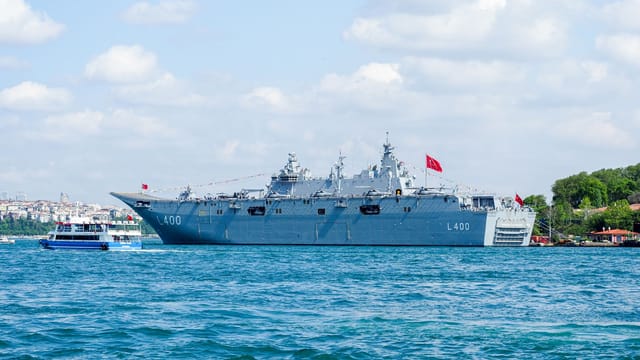 Turkish naval warship L400 in the Bosphorus, Istanbul, navigating the strait on a sunny day.