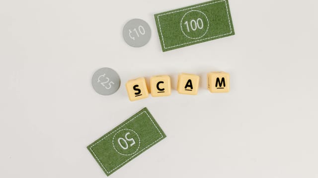 Flat lay of fake currency and scam letters on a gray surface representing financial deception.