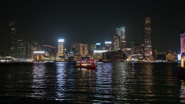Captivating view of Hong Kong skyline illuminated at night with ferries on Victoria Harbour.