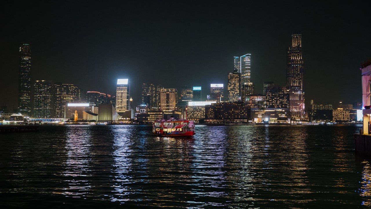 Captivating view of Hong Kong skyline illuminated at night with ferries on Victoria Harbour.