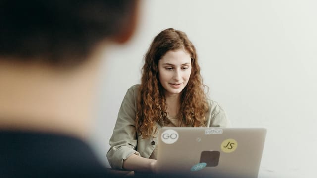 Young professional woman working on a laptop in an office setting, concentrating on her task.