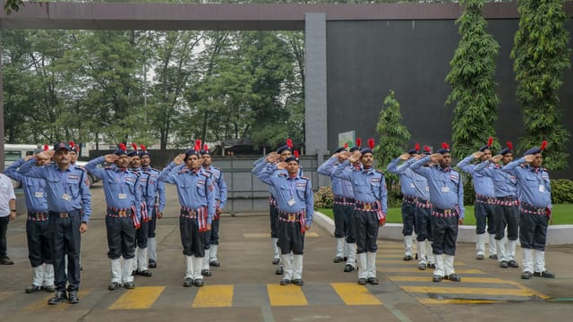 A group of uniformed personnel performing a salute outdoors, demonstrating discipline and unity.