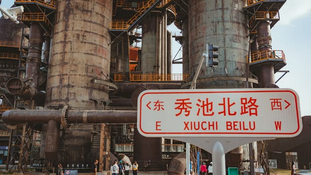 Urban view of a large industrial facility with a Xiuchi Beilu road sign in the foreground.