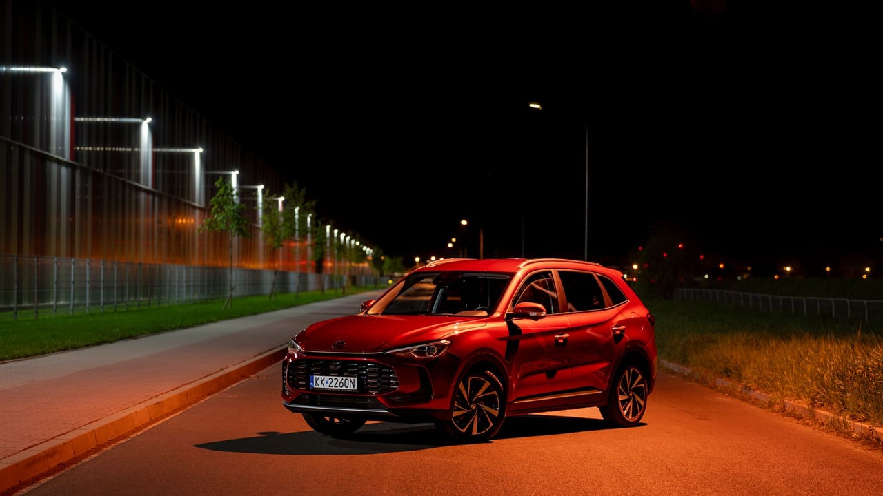Red SUV illuminated by streetlights at night in Kokotów, Poland. Modern urban vibe.