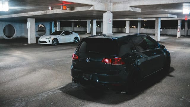 Contemporary prestige automobile parked on asphalt ground lighted with bright shiny lamps