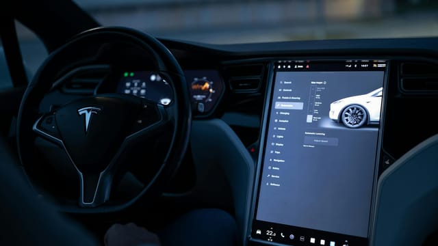 Tesla car interior showcasing advanced touchscreen display and steering controls.