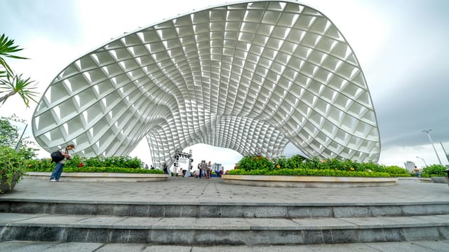 Photo of the iconic Apec Park landmark in Da Nang, Vietnam, featuring tourists and a cloudy sky.