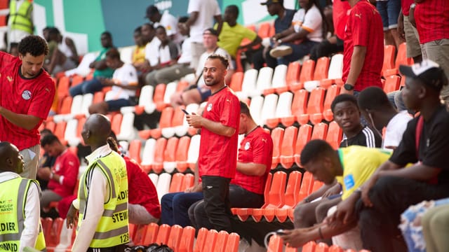 Diverse group of soccer fans wearing red jerseys at a lively stadium event.