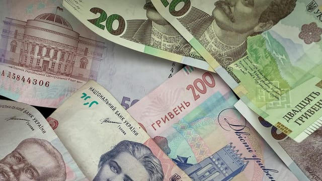 A vibrant assortment of Ukrainian Hryvnia banknotes featuring historical figures and architecture.