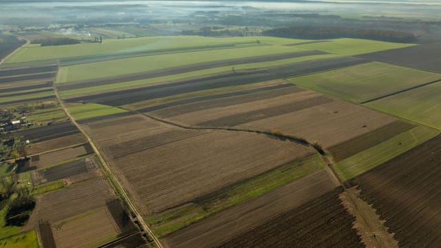 Expansive aerial shot of agricultural fields in Garešnica, Croatia, during daytime.