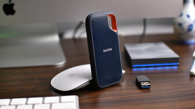 Close-up of a desk setup featuring external hard drives, mouse, and USB stick.