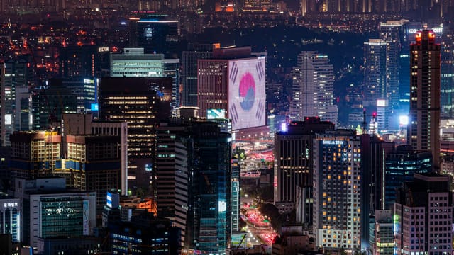 Vibrant night skyline of Seoul featuring illuminated skyscrapers and urban landscape.