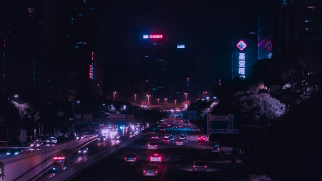 Illuminated city street with vibrant lights and traffic in downtown Guangzhou at night.