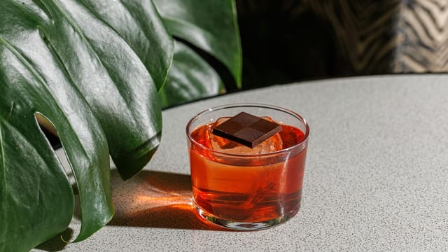A vibrant Negroni cocktail garnished with dark chocolate, perfect for an exotic beverage experience.