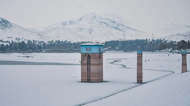 A picturesque winter view of the Qargha Reservoir surrounded by snowy mountains in Kabul, Afghanistan.