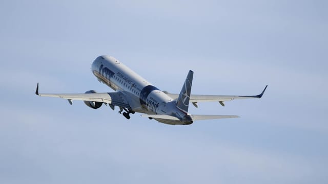 A commercial airplane ascends into a clear blue sky, showcasing modern aviation.