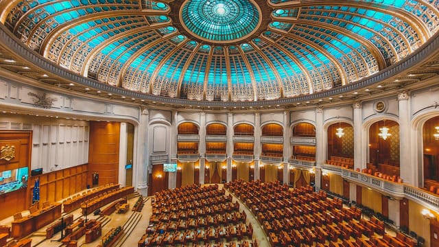 Vibrant interior of a parliament hall with a grand dome and intricate architecture.