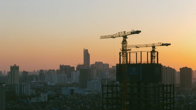 Silhouette of construction cranes against a sunset backdrop in Wuhan, China.