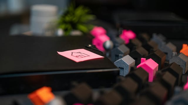 Close-up of model houses and a house sketch on a sticky note, symbolizing real estate concepts.