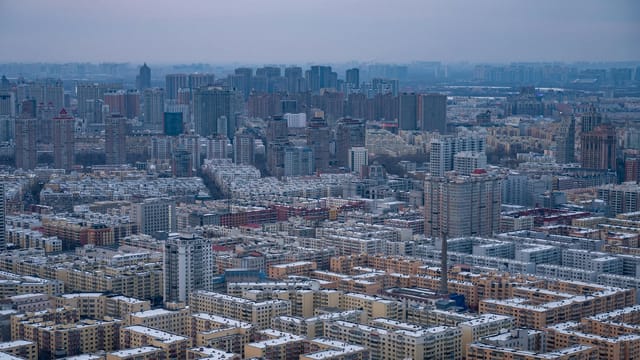 Expansive view of Harbin city skyline under a winter sky, showcasing dense urban architecture.